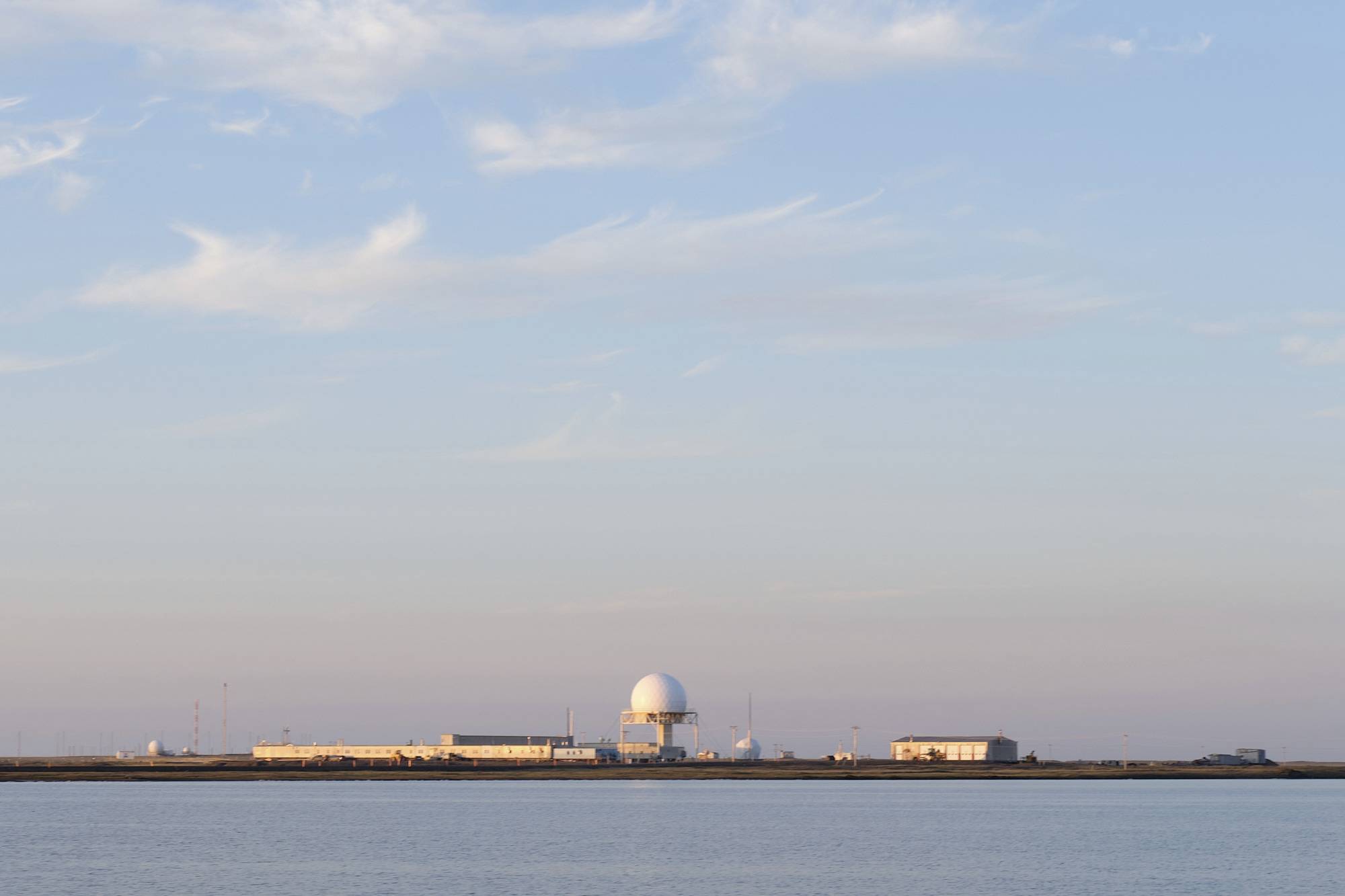 The DEW line. a building across a lake with military radar towers